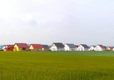 Ackerfläche im Vordergrund, Neubaugebiet im Hintergrund